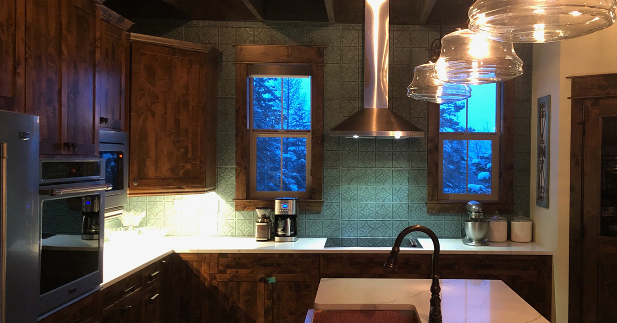 Moody kitchen with dark wood cabinets and tin tile backsplash that goes all the way to the ceiling.