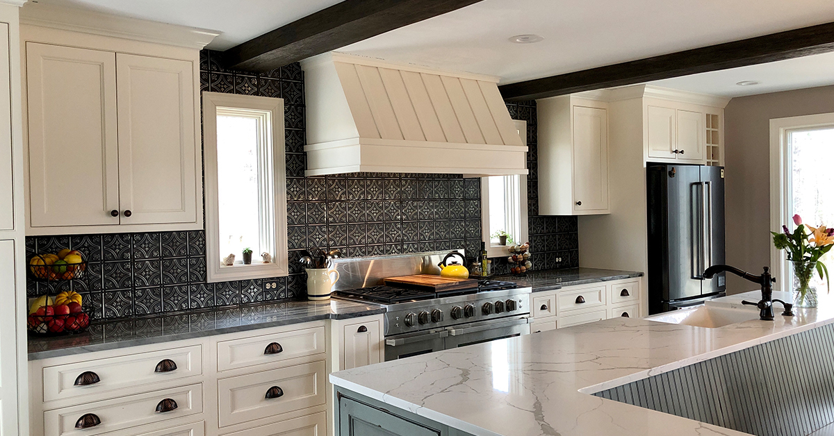 Large black and white kitchen with silver and black tin tile backsplash.